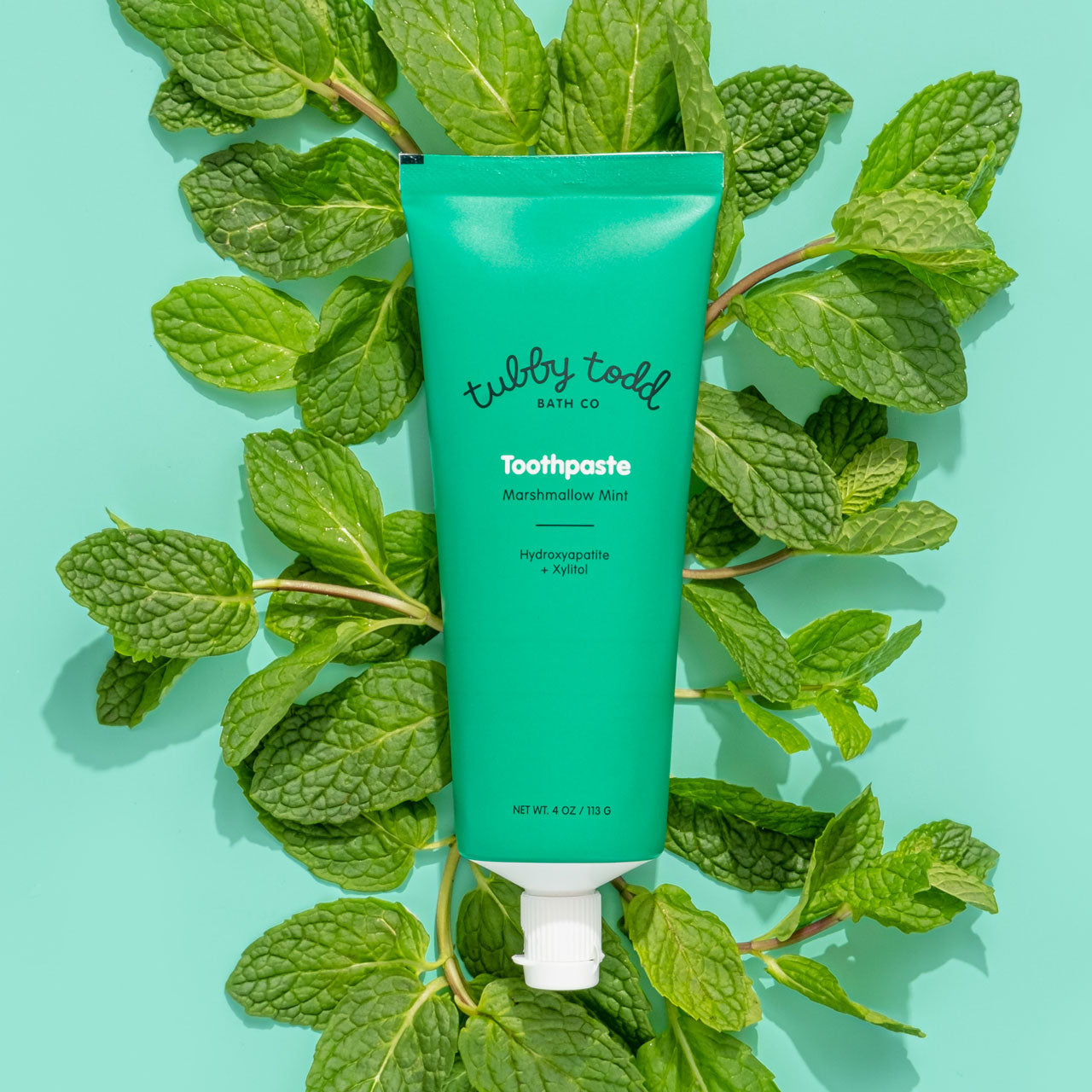 Marshmallow Mint Hydroxyapatite Toothpaste laying in bed of mint leaves